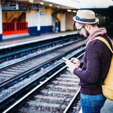 hombre consultando teléfono en estación de tren