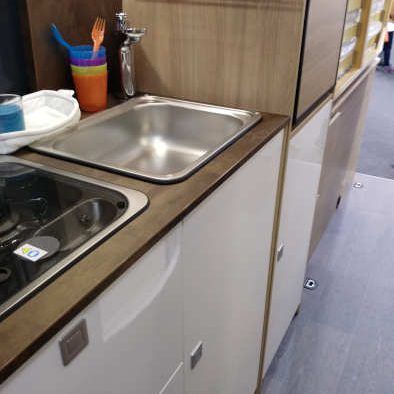 cocina con muebles bajos y nevera elevada en furgoneta