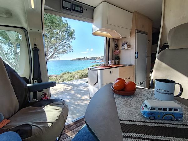 interior de la camper de alquiler de VandeCamper con vistas al mar desde el comedor