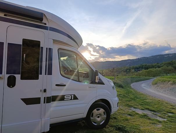 atardecer con autocaravana de alquiler de VandeCamper en primer plano y carretera de montaña al fondo