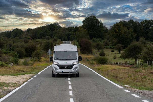 furgoneta de Van de Camper de alquiler circulando por carretera al atardecer